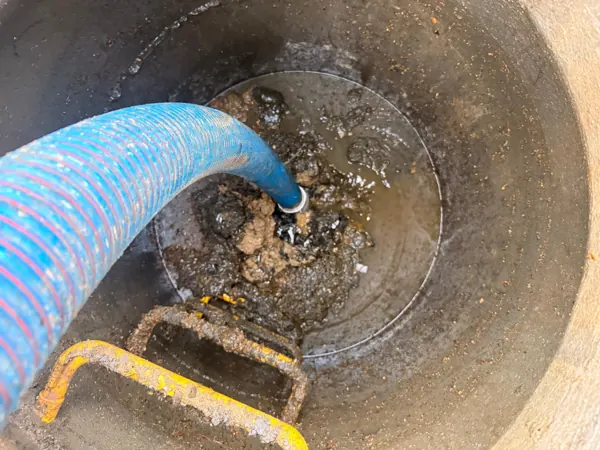 Tuyau d'aspiration du camion hydrocureur plongé dans un regard