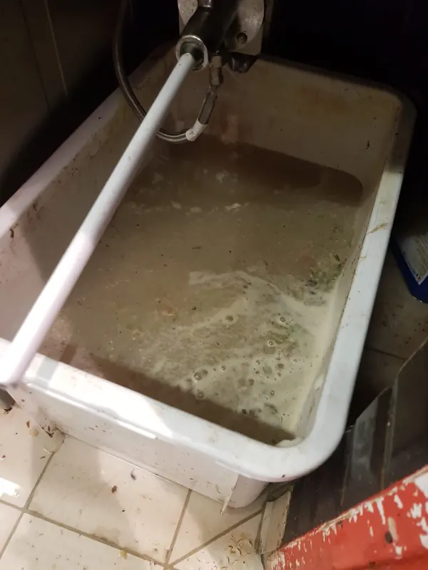 Bac de plonge d'une cuisine professionnelle bouché, rempli d'eau grasse