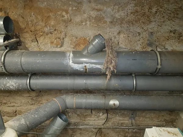 Collecteur en PVC dans une cave d'immeuble, lingettes sorties par le tampon de visite