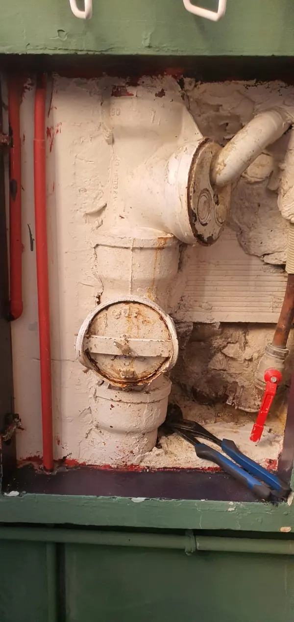 Colonne d'évacuation en fonte avec deux tampons de visite dans une gaine technique d'immeuble