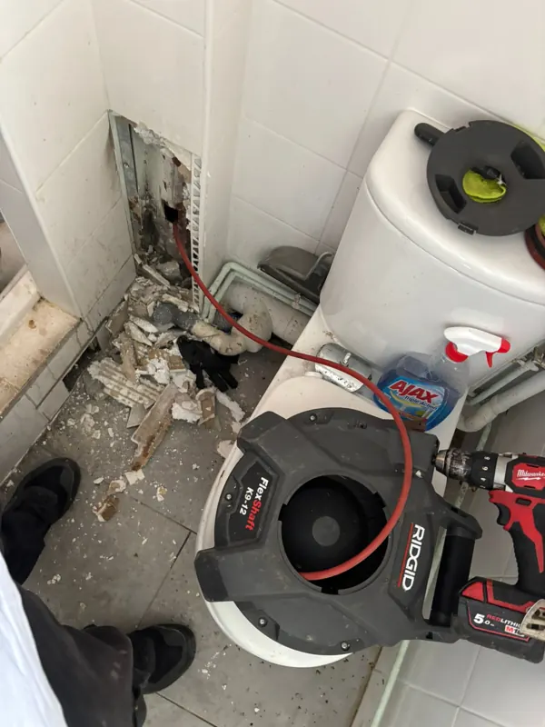 Furet électrique à tambour posé au pied d'un WC pendant un débouchage